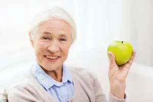 dental implants patient holding an apple