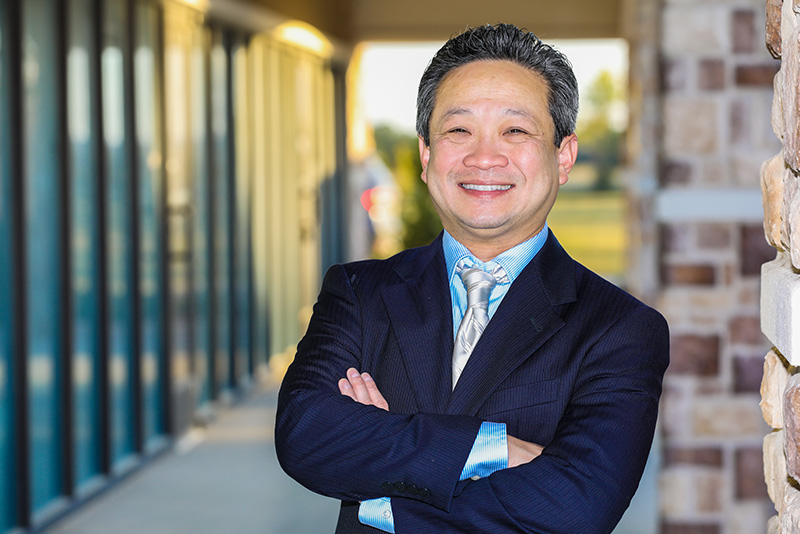 Dr. Long Nguyen Standing Professionally In Front Of One Of The iSmile Dental Offices